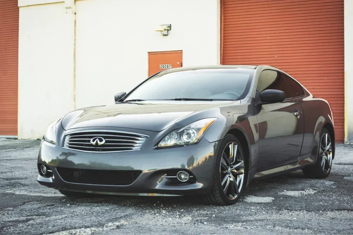 Gray Infiniti coupe parked in front of orange garage doors