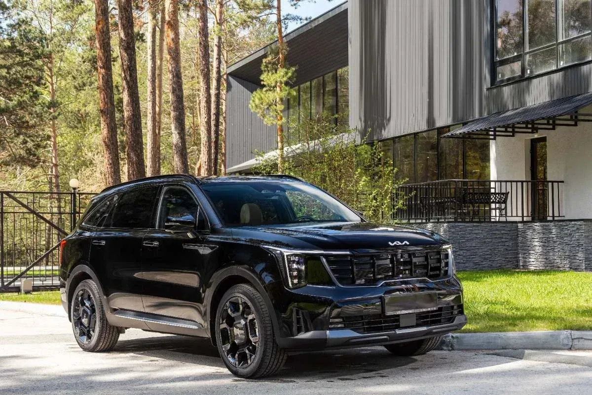 Black SUV parked beside a modern house with trees in the background