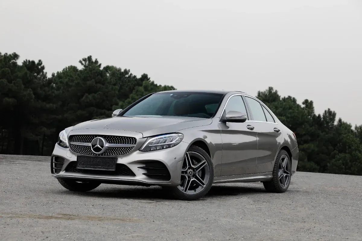 Silver Mercedes sedan parked on a road with trees in the background