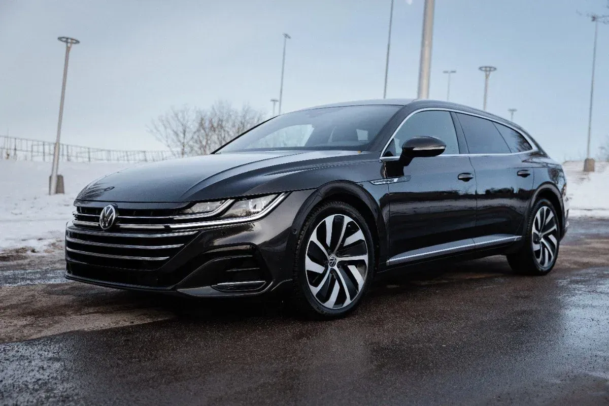Black Volkswagen sedan parked on a snowy lot under an overcast sky