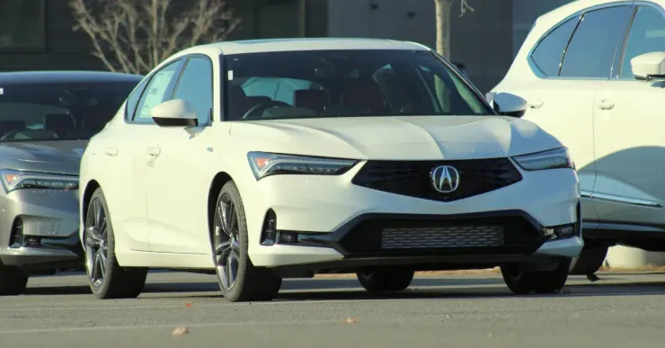 White Acura sedan driving on a road with other cars in the background