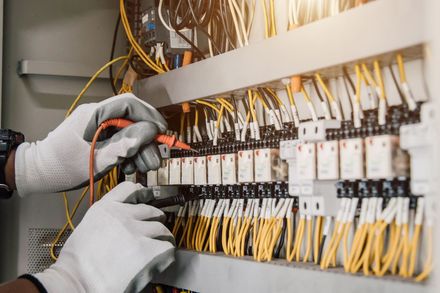 Un elettricista sta lavorando su un quadro elettrico con un multimetro.