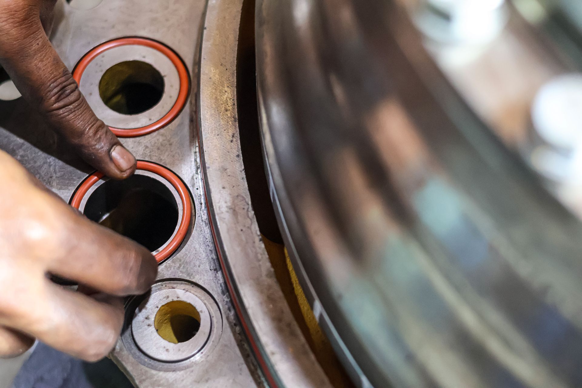 Close view of the hand of a mechanic putting an O-ring on a mechanical part.