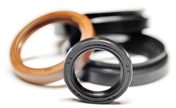 Close-up of several circular oil seals, some black and one tan, against a white background.