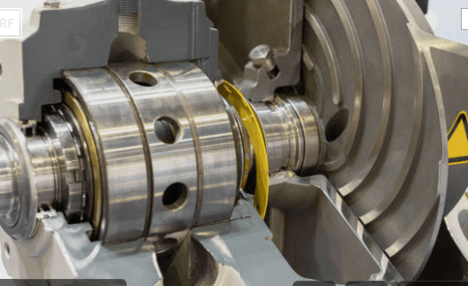 Cutaway view of mechanical gears and bearings, metallic silver, with a yellow curved piece.