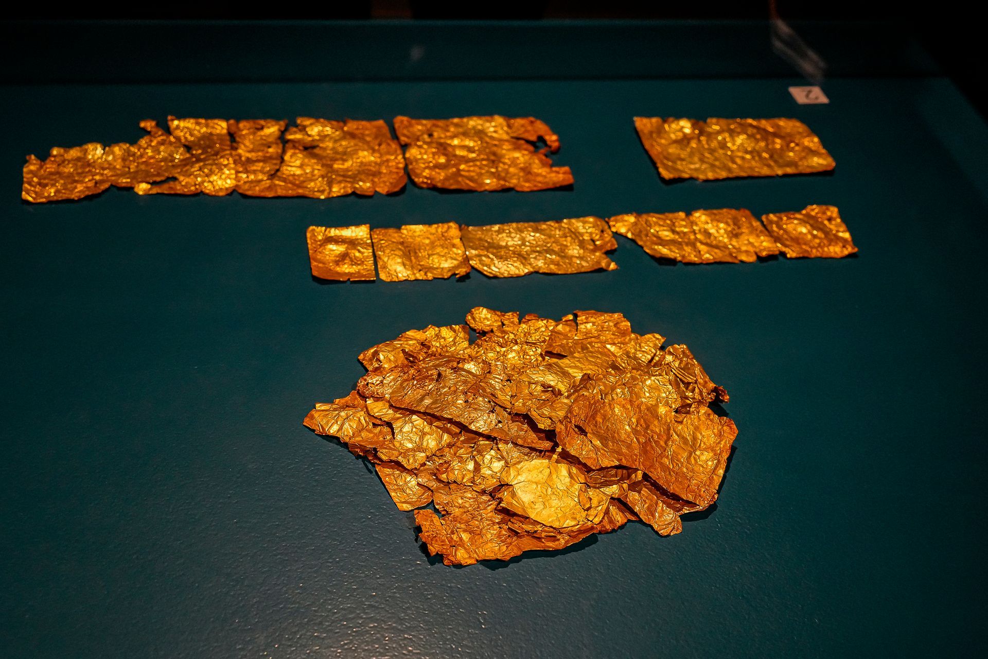 Fragments of smooth gold foil bands on display in the case