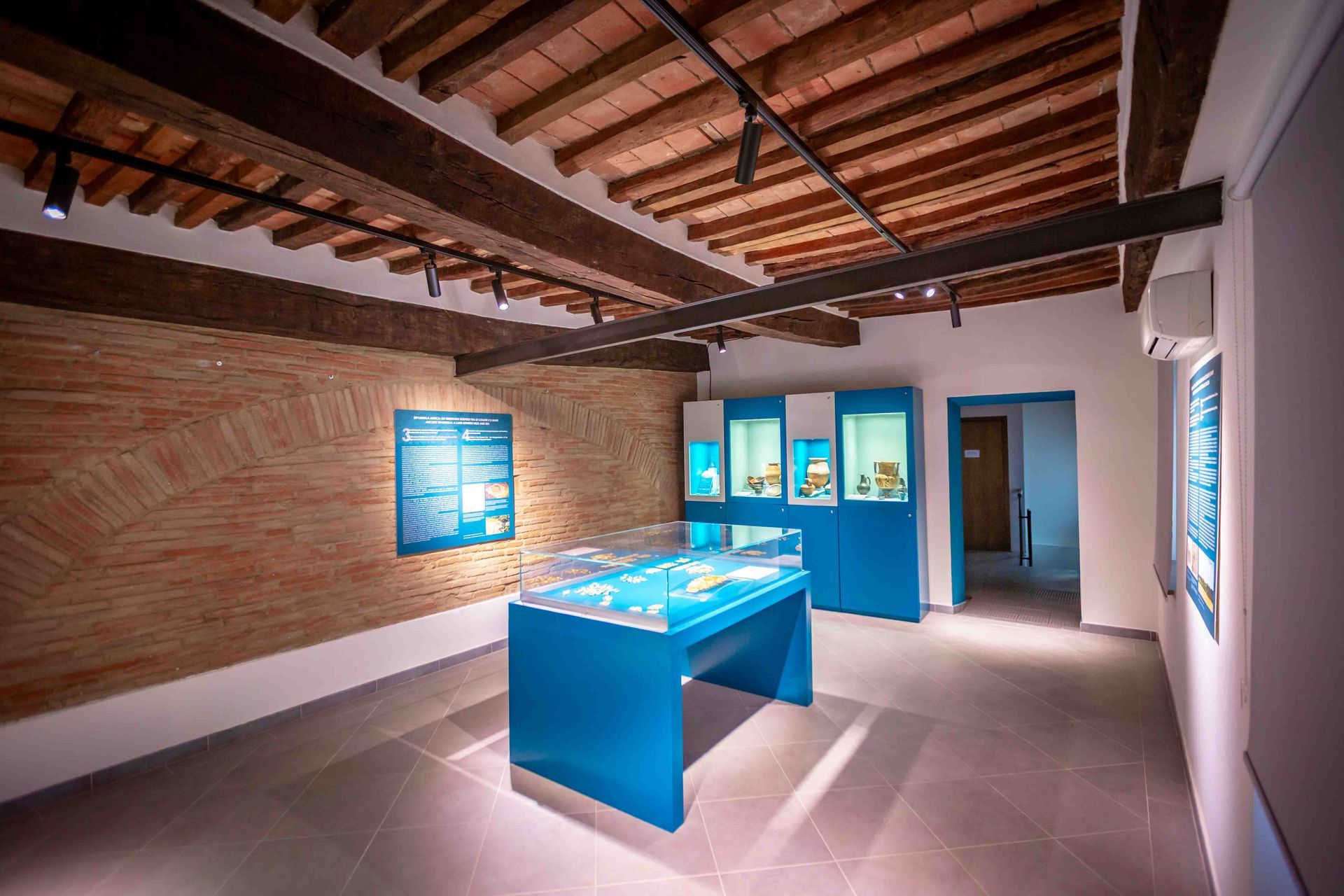Display cases with ceramics beneath the beamed ceiling of the restored rooms