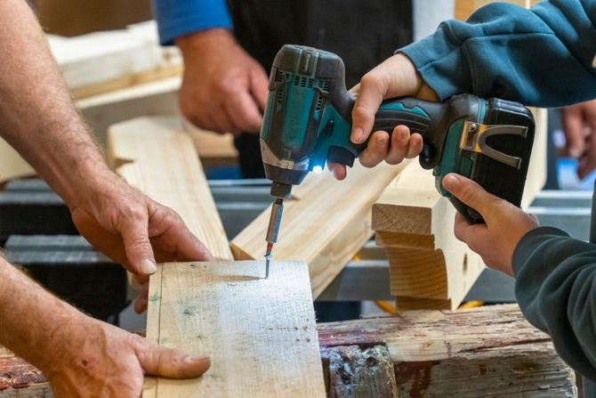 People drilling and holding wood planks during a carpentry project