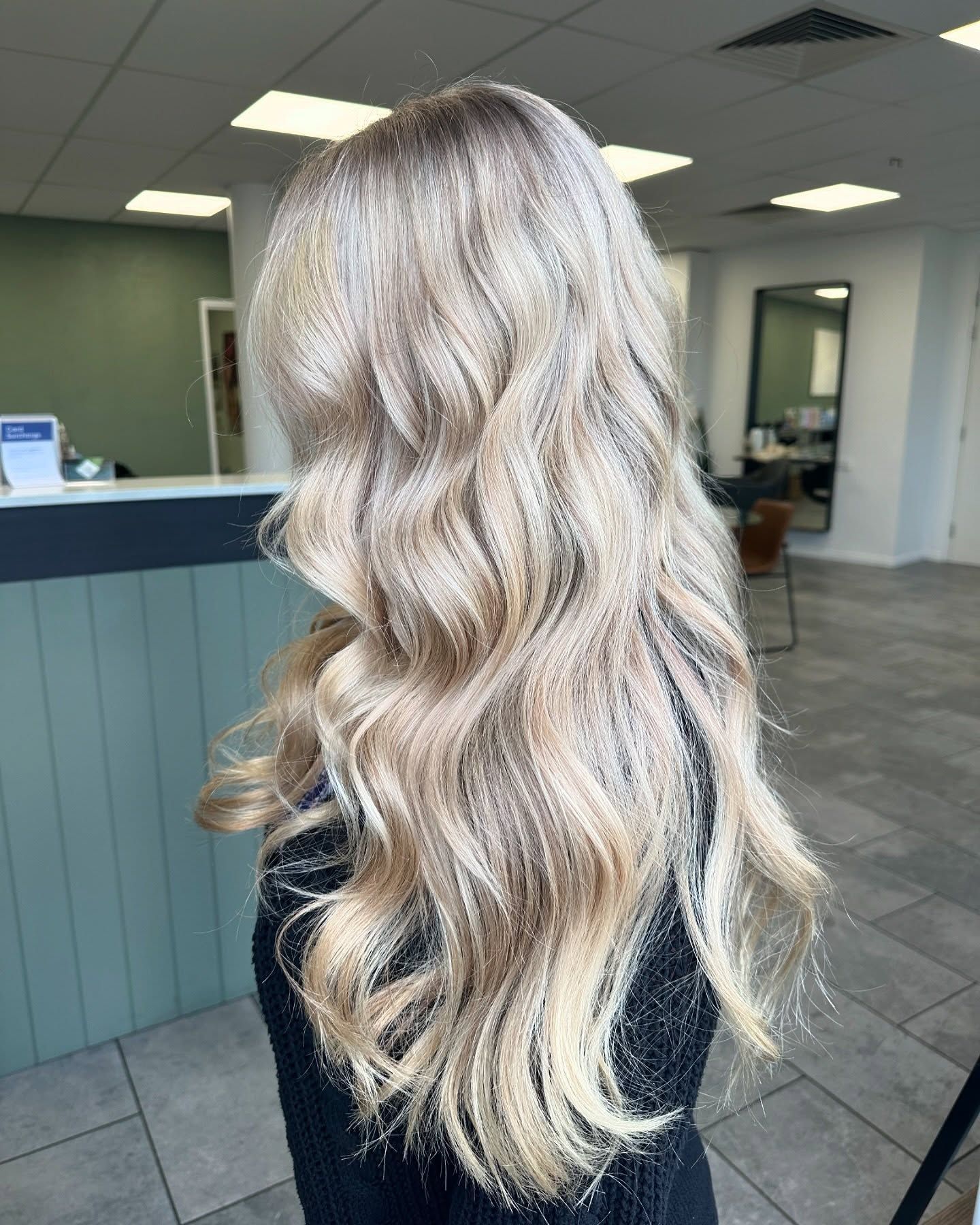 A Woman With Long Blonde Hair is Wearing a Grey Shirt — Blackwell Hair In Woree, QLD