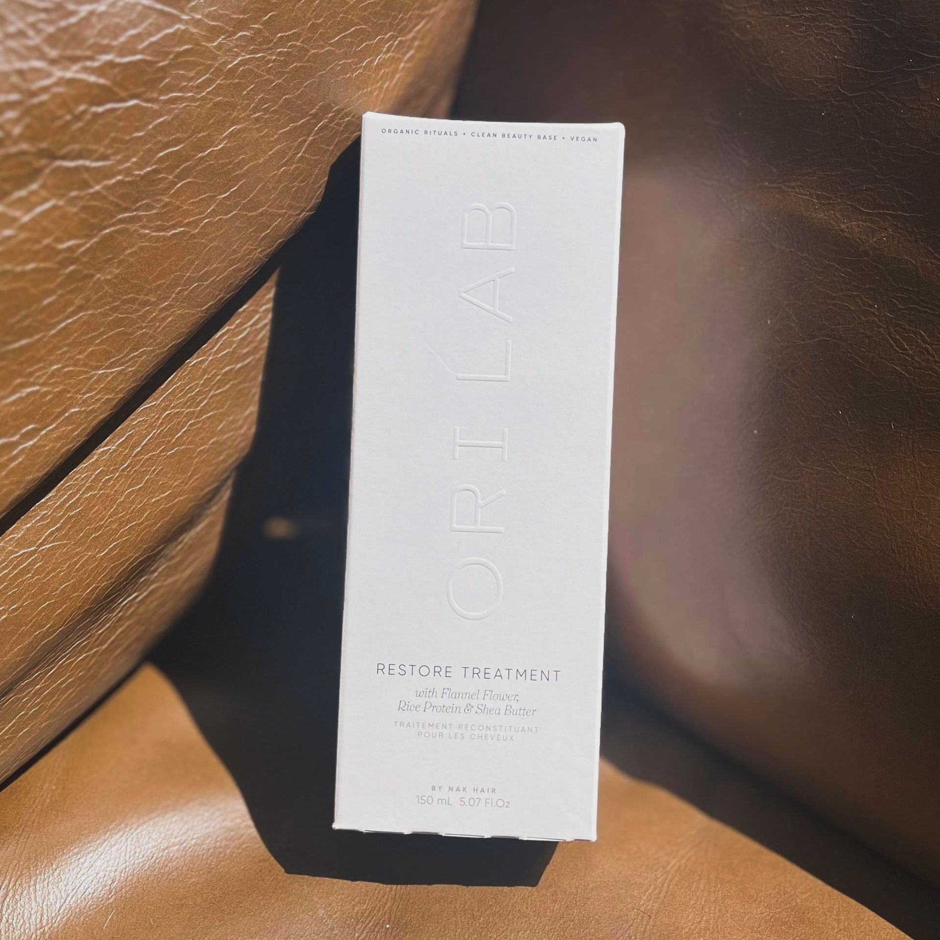 A White Box Of Ori Lab Hair Product Is Sitting On A Brown Leather Chair — Blackwell Hair In Woree, QLD