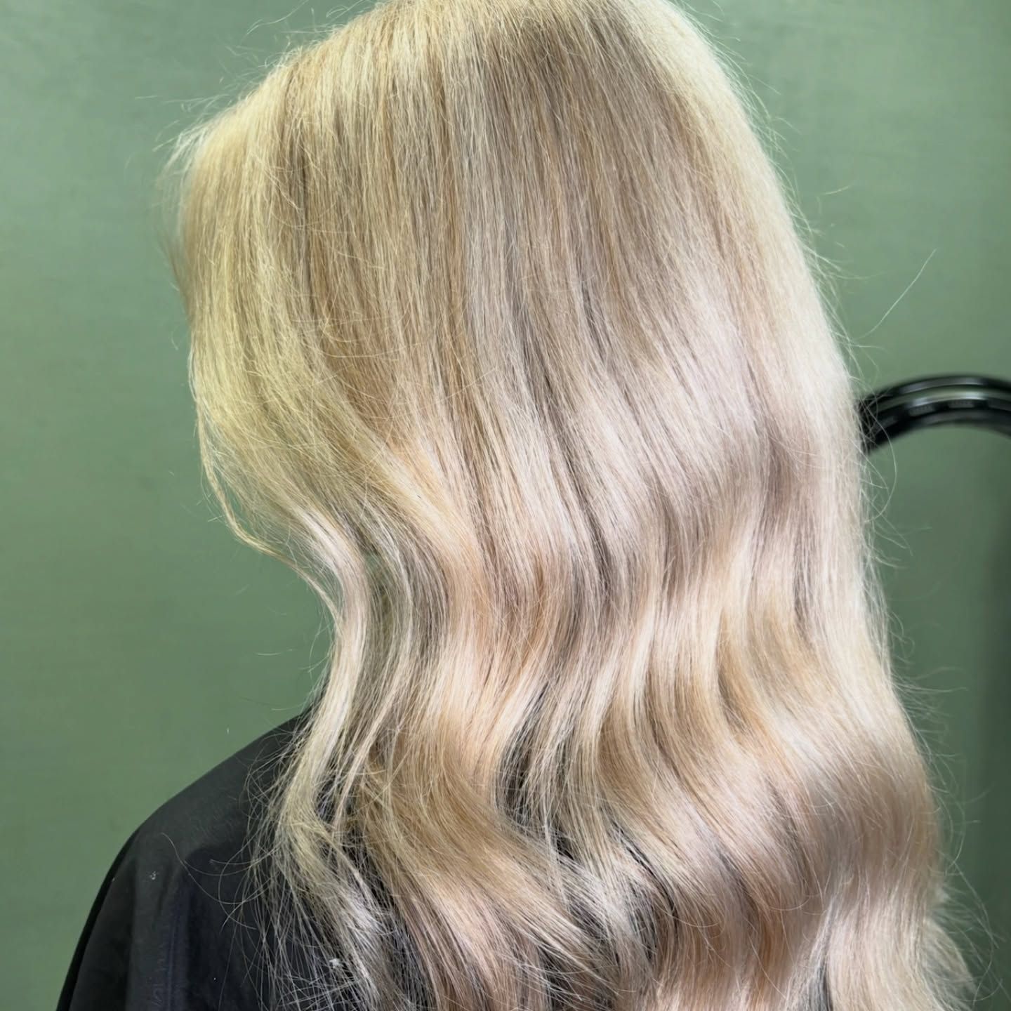 Wavy Platinum Blonde Hair Cascading Over A Black Top Against A Green Background — Blackwell Hair In Woree, QLD