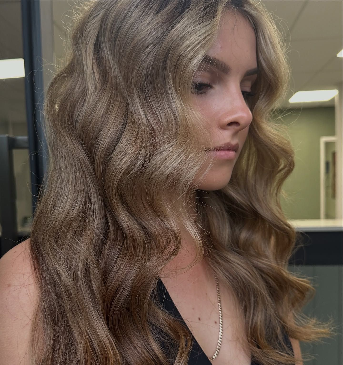 Side Profile Of A Woman With Wavy Blonde Hair In A Hallway — Blackwell Hair In Woree, QLD