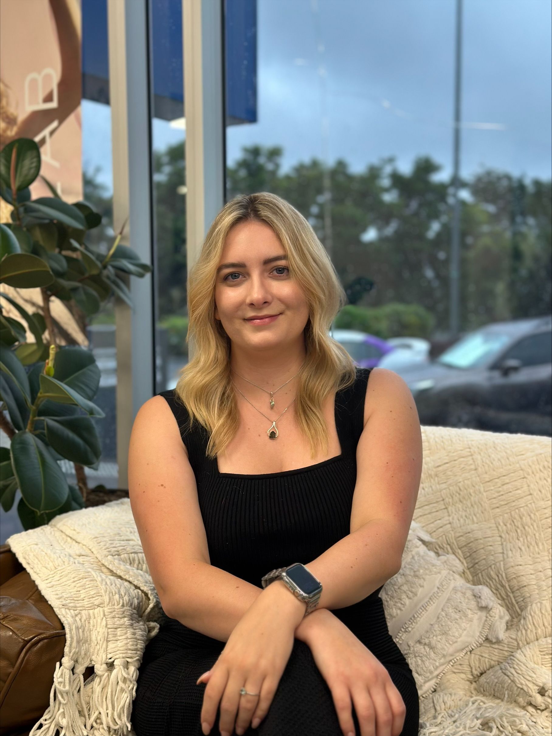 A woman in a black dress is sitting on a couch — Blackwell Hair In Woree, QLD