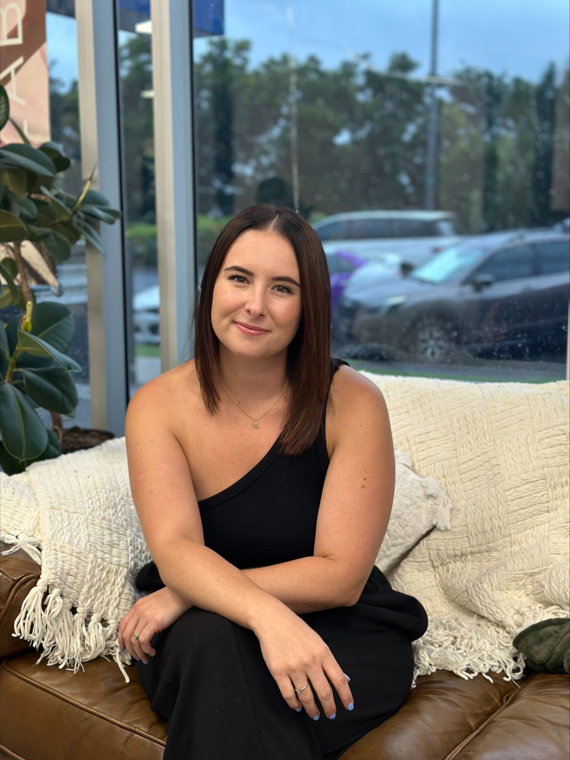 A woman in a black dress is sitting on a couch — Blackwell Hair In Woree, QLD