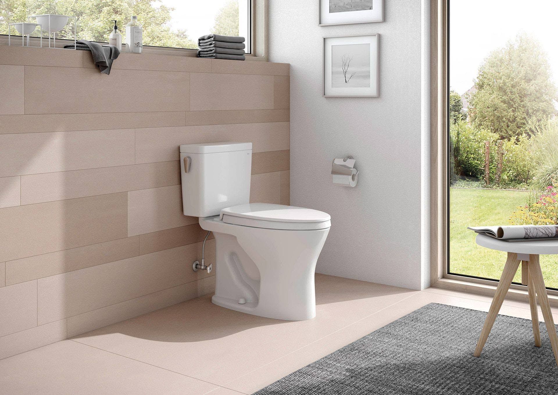 Modern bathroom with a white toilet beside a large window and a view of greenery outside.