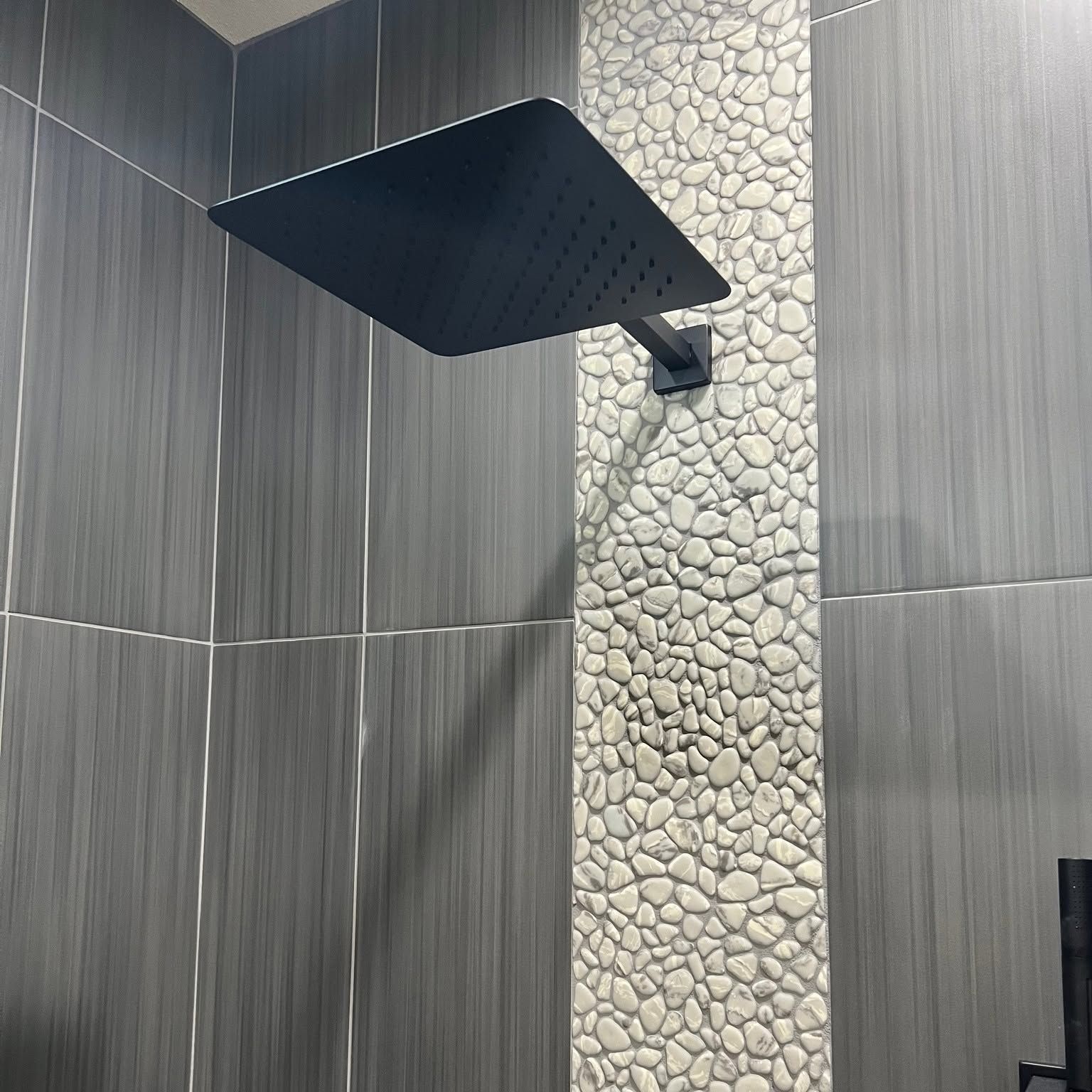 Modern shower with black rainfall showerhead and gray stone-tile wall