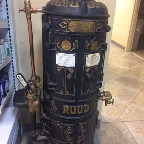 Black vintage cast-iron stove or heater with ornate gold trim in a tiled indoor room