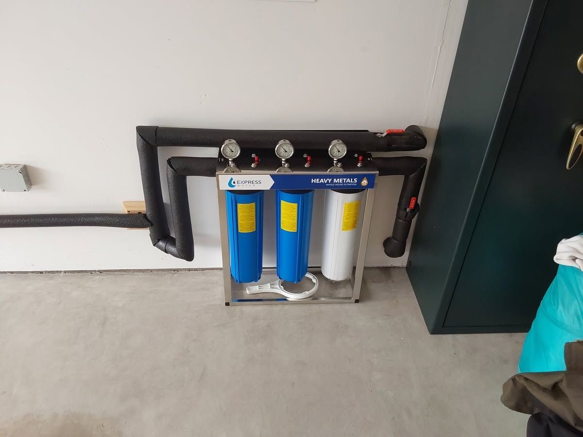 Wall-mounted water filtration system with blue and white cylinders in a utility room corner