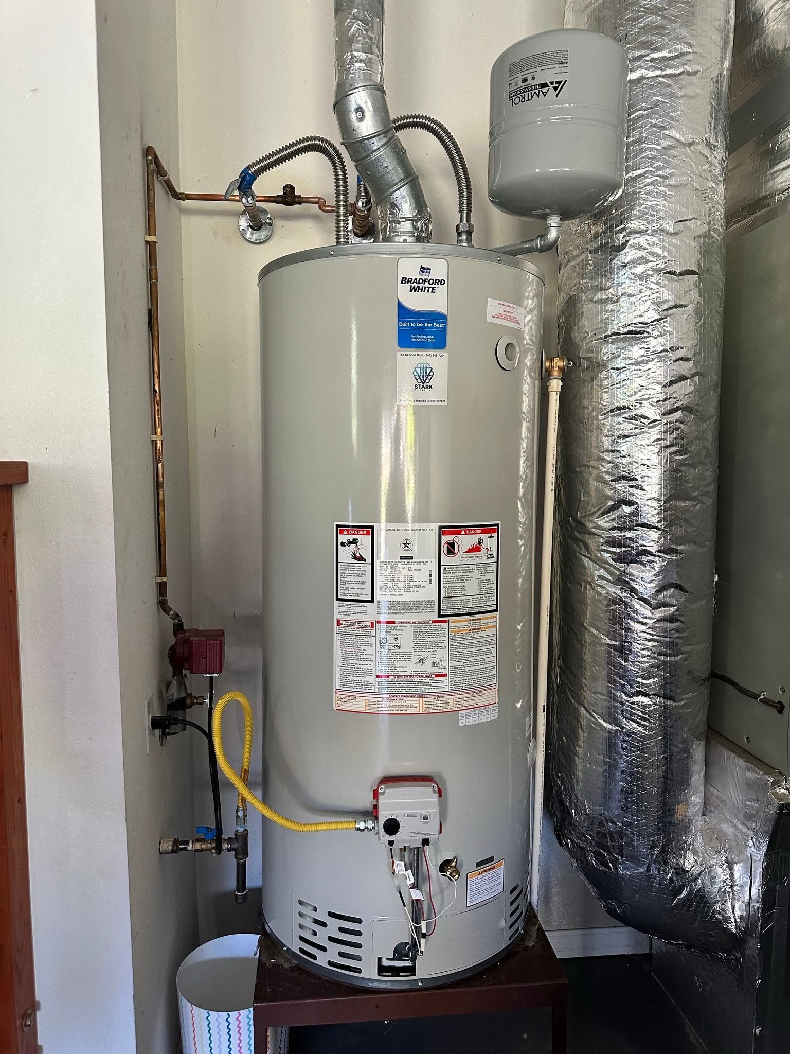 Water heater with foil-wrapped ducting and pipes in a utility closet.