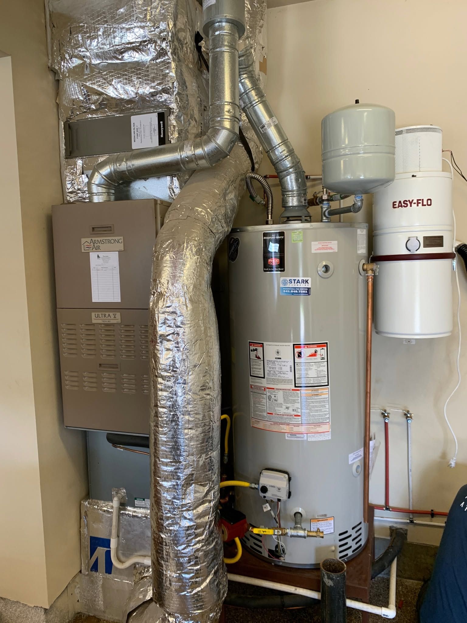 Home utility closet with water heater, furnace, and insulated ductwork.
