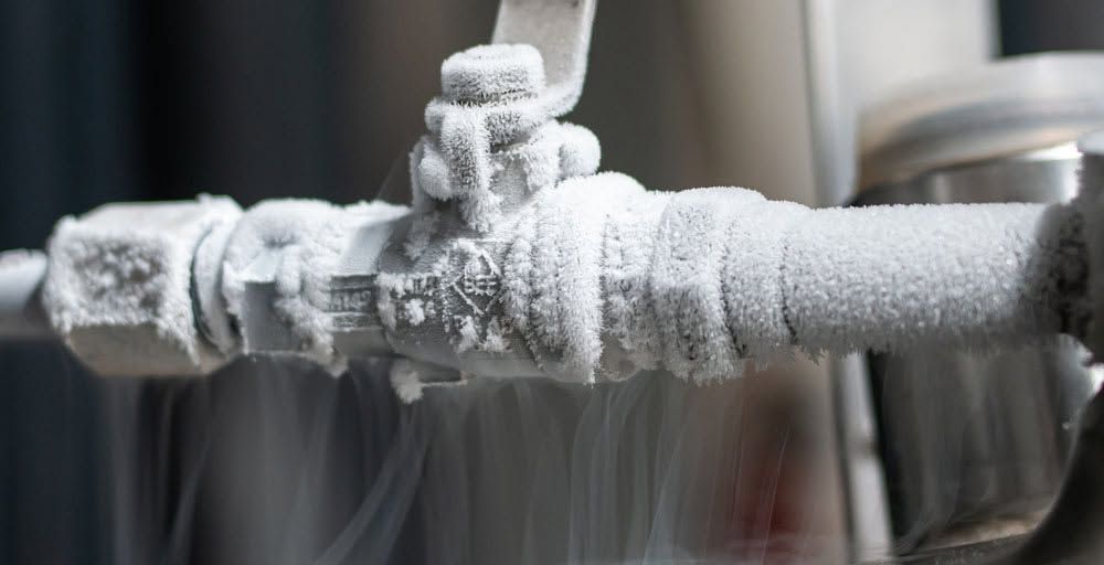 Frozen metal pipe valve coated in thick frost and ice crystals