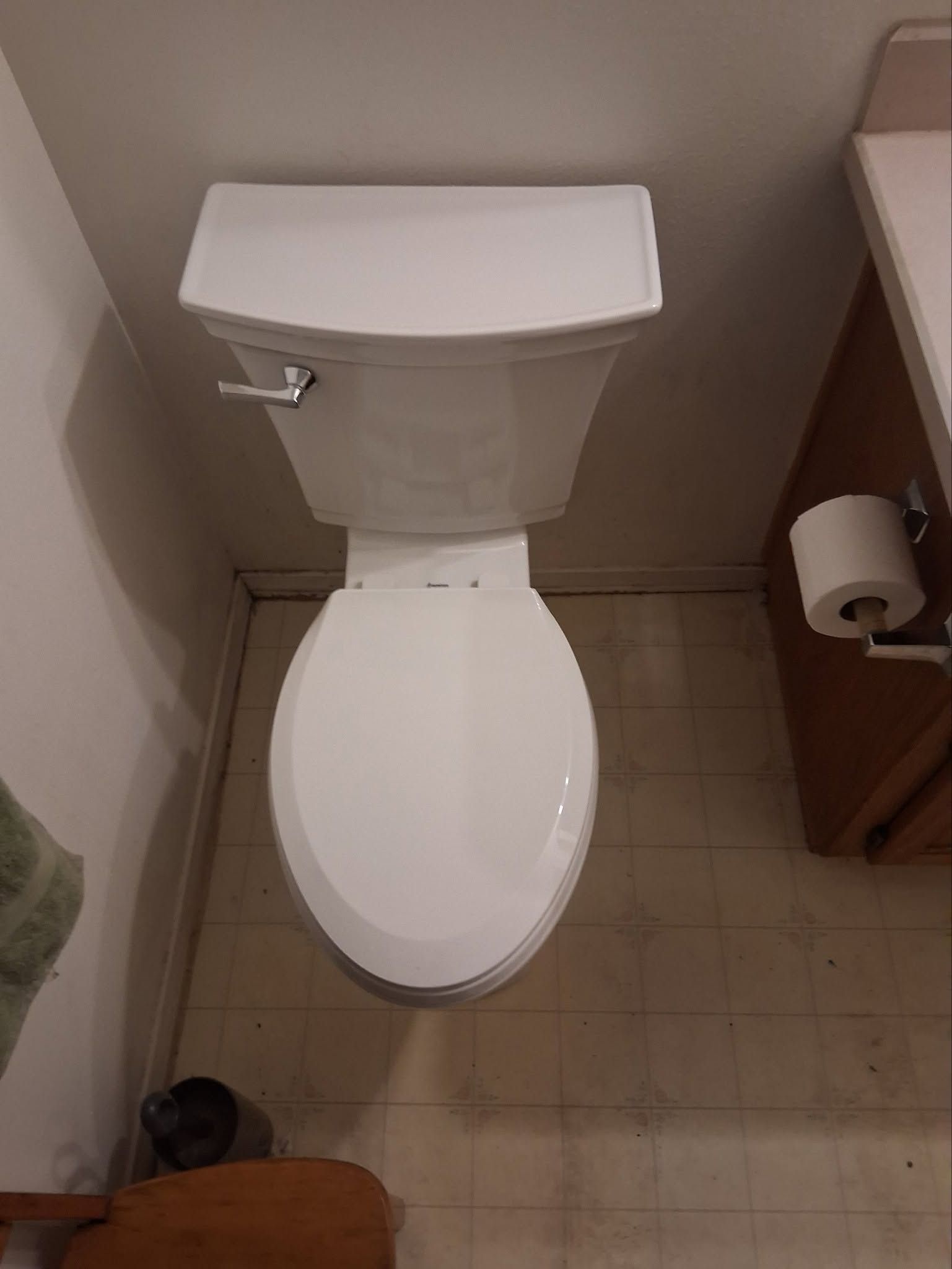 Small bathroom with a white toilet, beige walls, and a toilet paper holder on the right.
