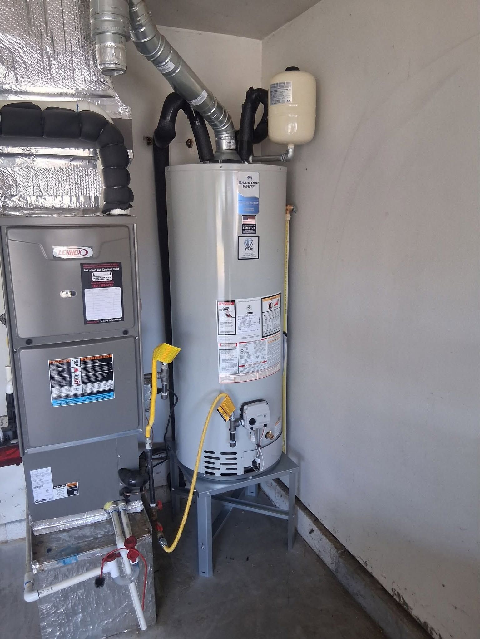 Residential utility closet with furnace, water heater, and ductwork along a white wall.
