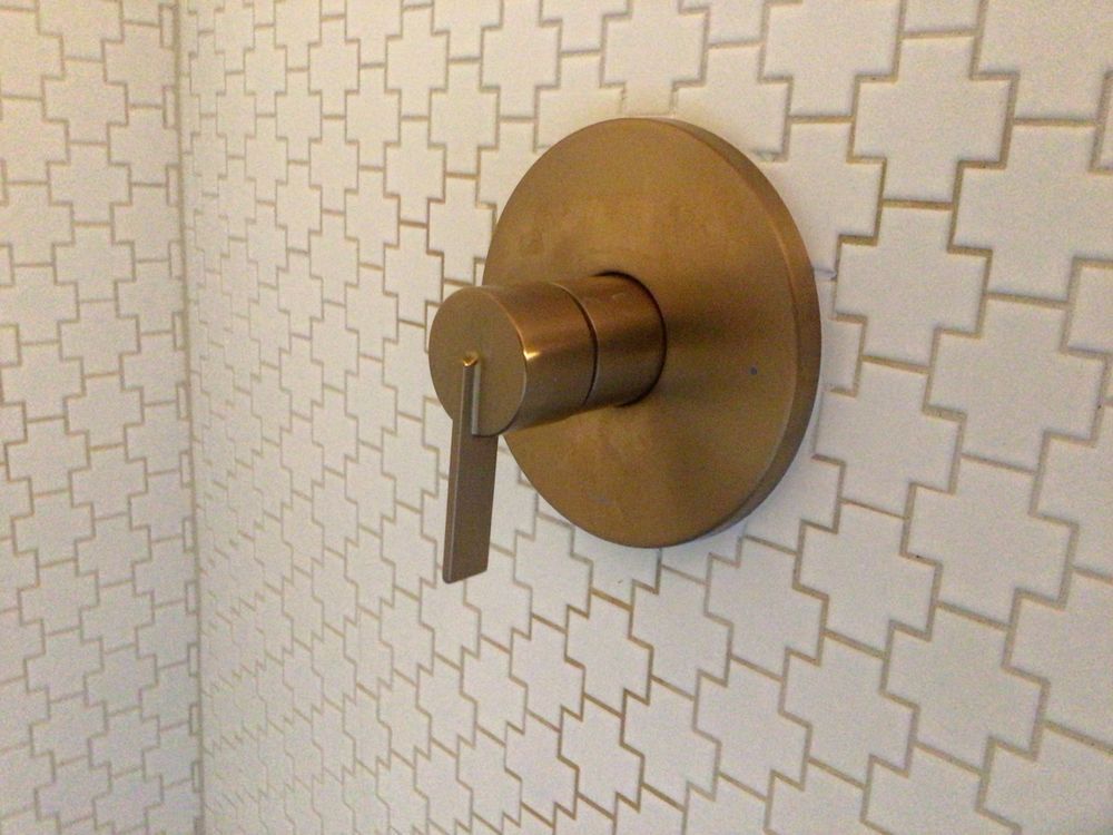 Brass door handle on a patterned wall-mounted plate against geometric wallpaper.