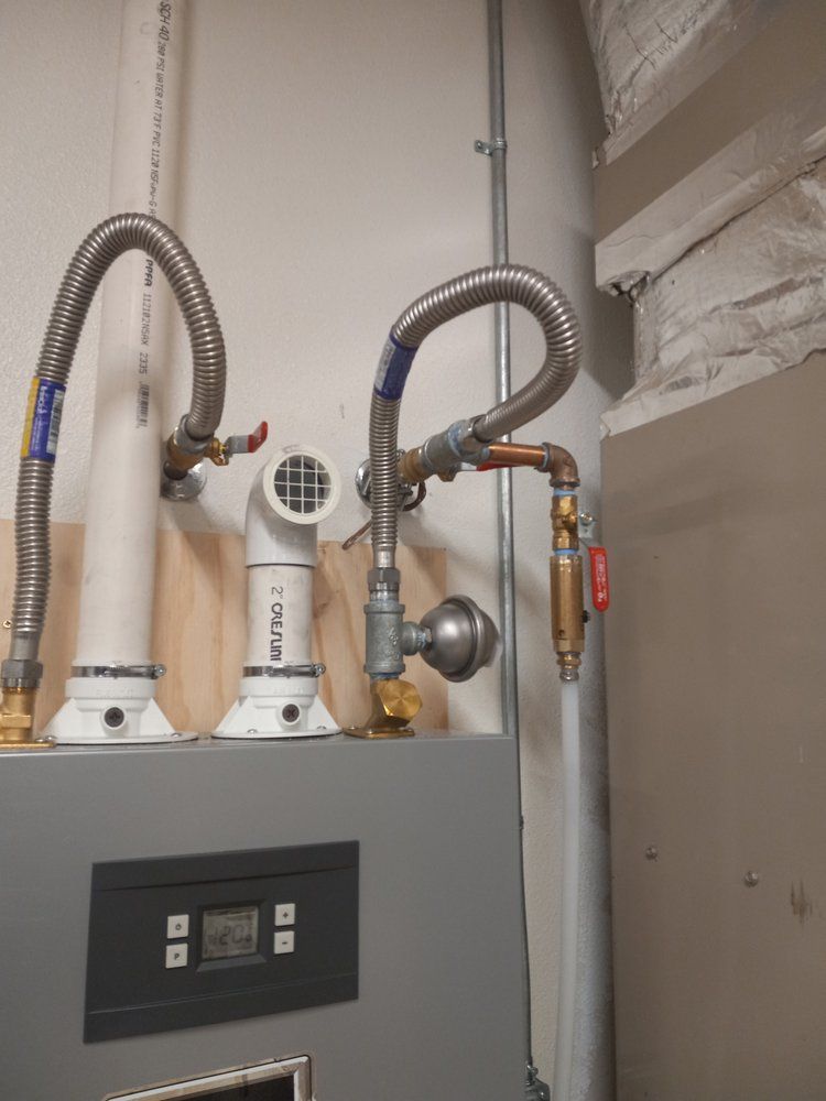 Gray water heater with hoses, pipes, and control panel in a utility closet.