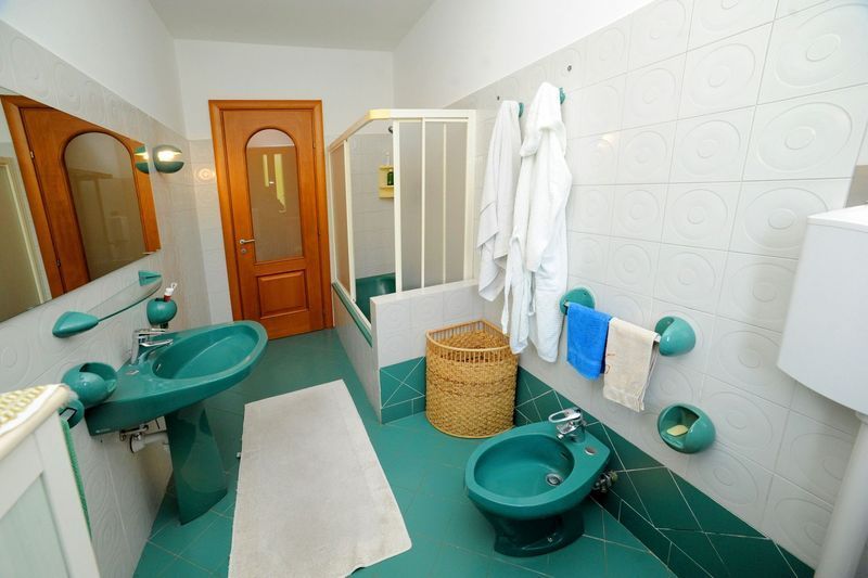 Bagno con sanitari verdi, pareti bianche e doccia, dotato di WC, lavandino, bidet e vasca.