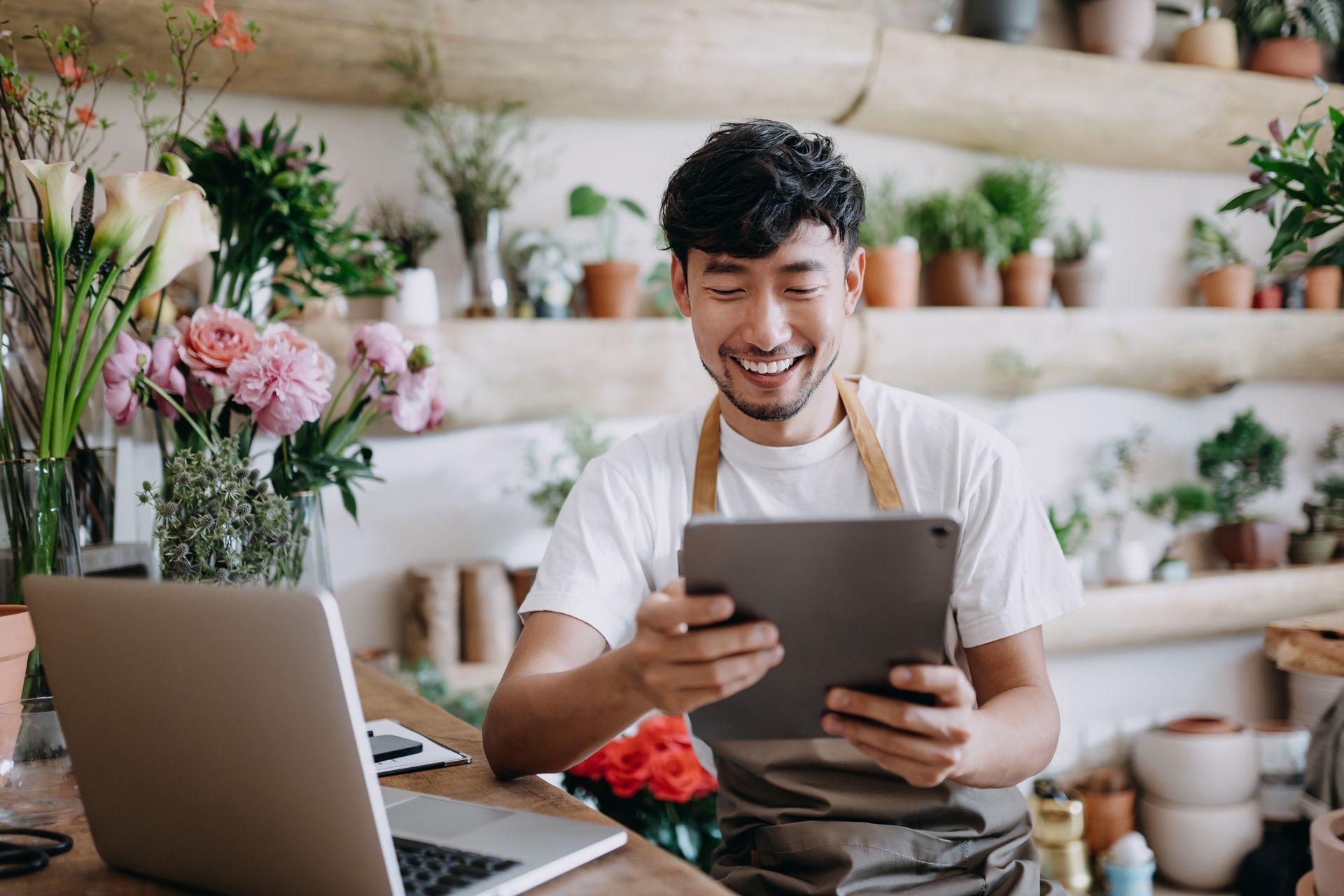 A man is sitting at a table with a laptop and a tablet.