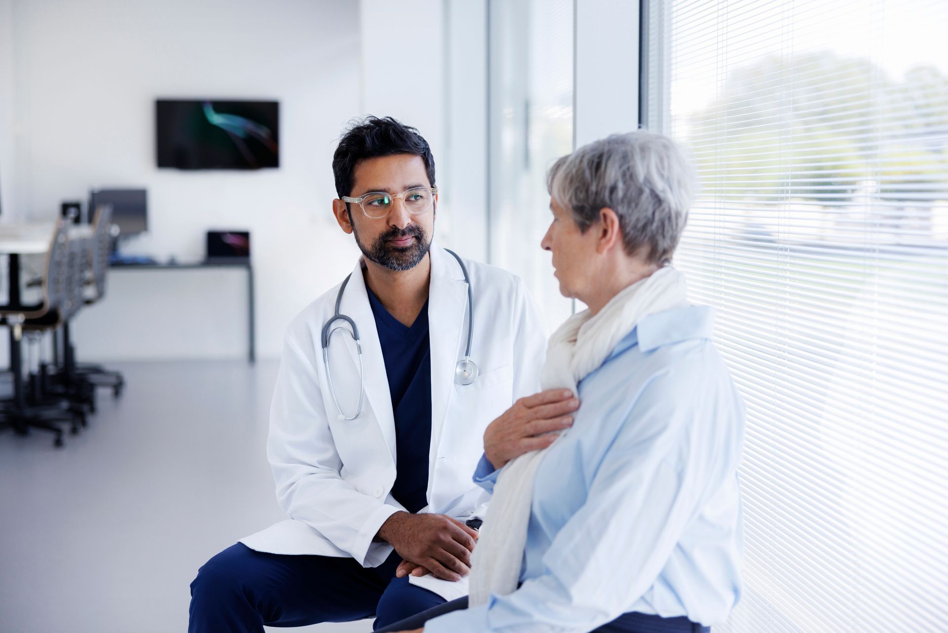 A doctor is talking to an elderly woman in a hospital room.