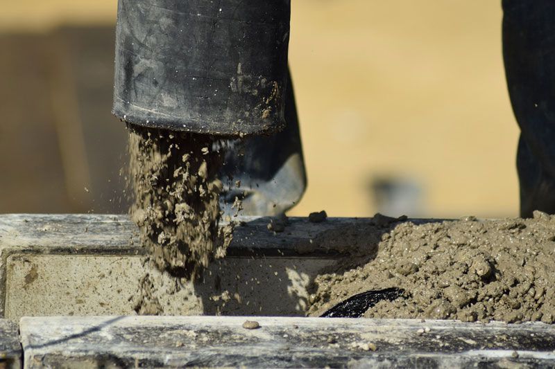A person is pouring concrete into a concrete block.