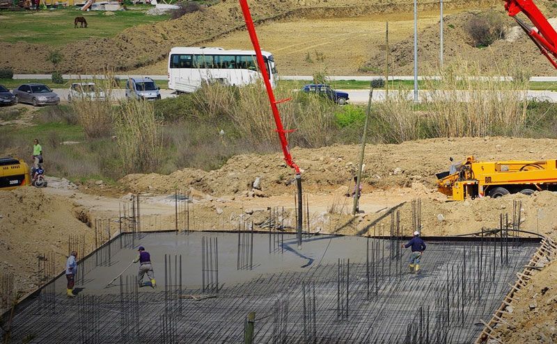 A construction site with a crane pumping concrete into the ground.