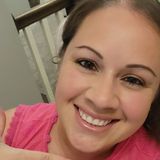 Smiling woman in a pink top, close-up indoors with a staircase in the background