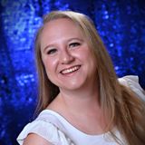 Smiling person in a white top against a blue, sparkly background