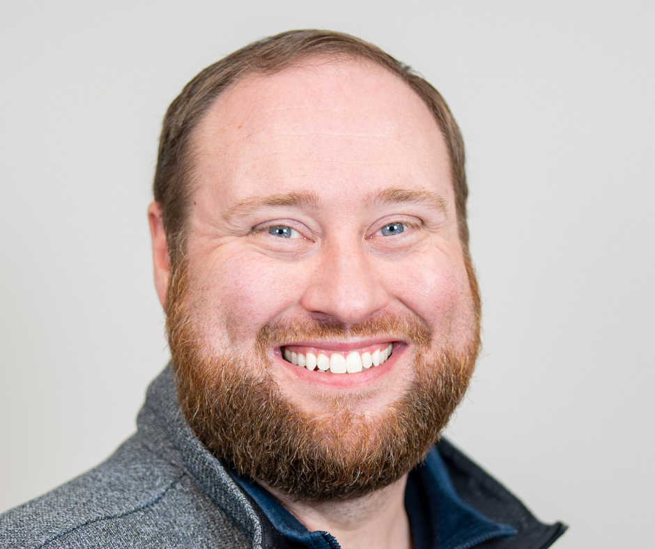 Smiling bearded man in a gray sweater against a light background