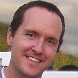 Smiling man outdoors with a blurred landscape background