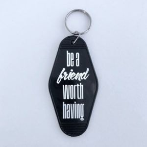 Black keychain tag with the words “be a friend worth having” in white text.