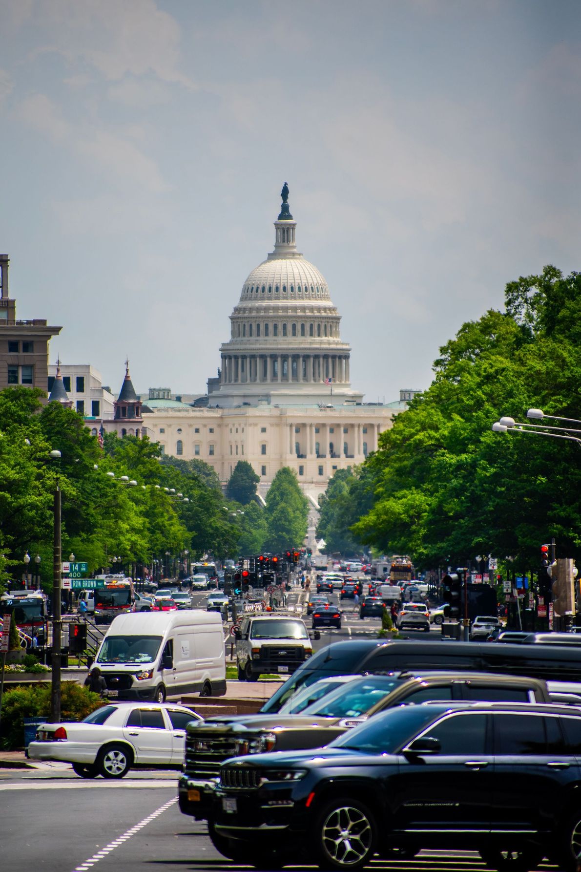 Aerial view of a white domed capitol building amid trees and surrounding city buildings at dusk