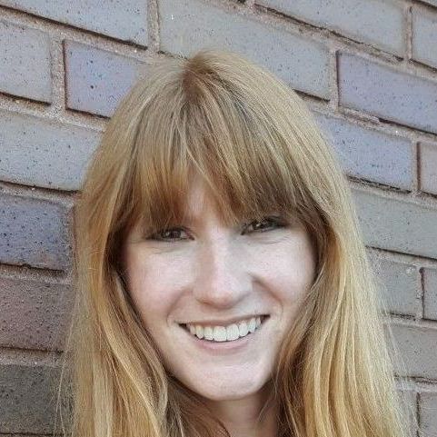 A portrait of a smiling woman with strawberry blonde hair