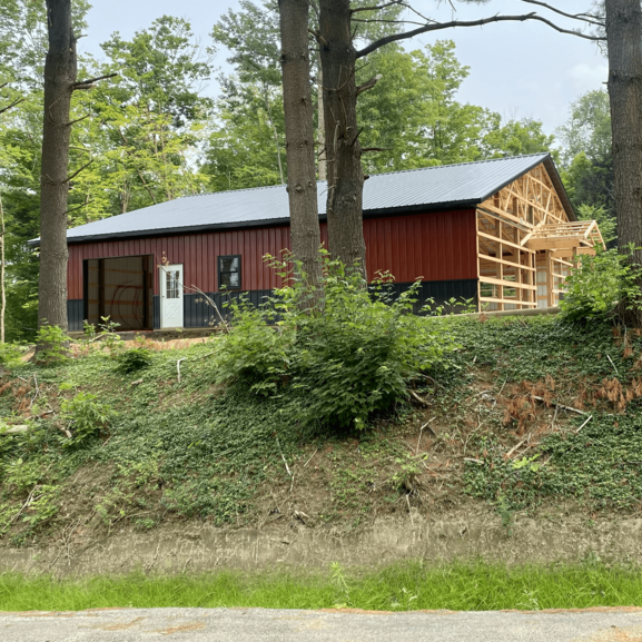 A red barn is being built in the middle of a forest