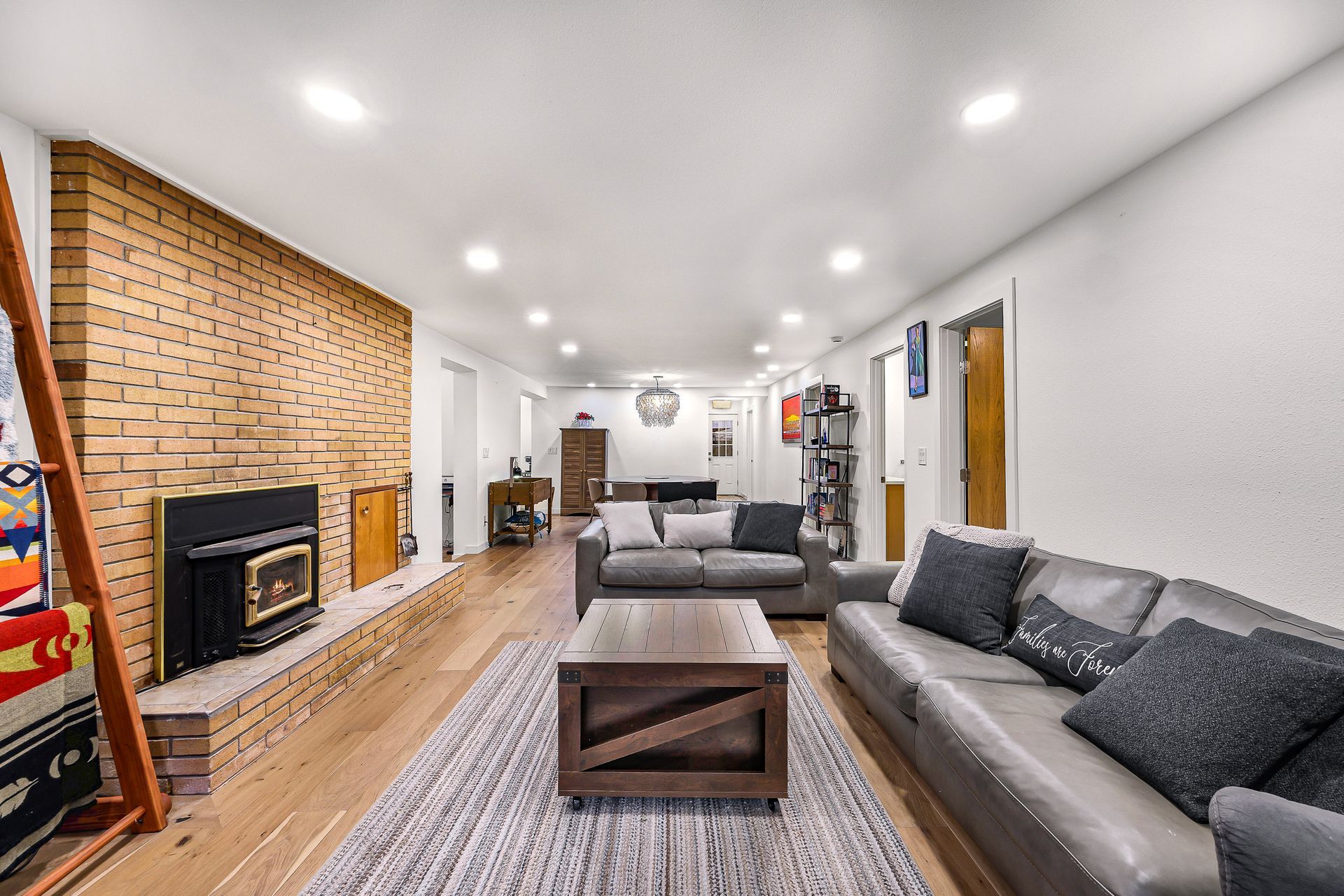 Living room with brick fireplace and large windows.
