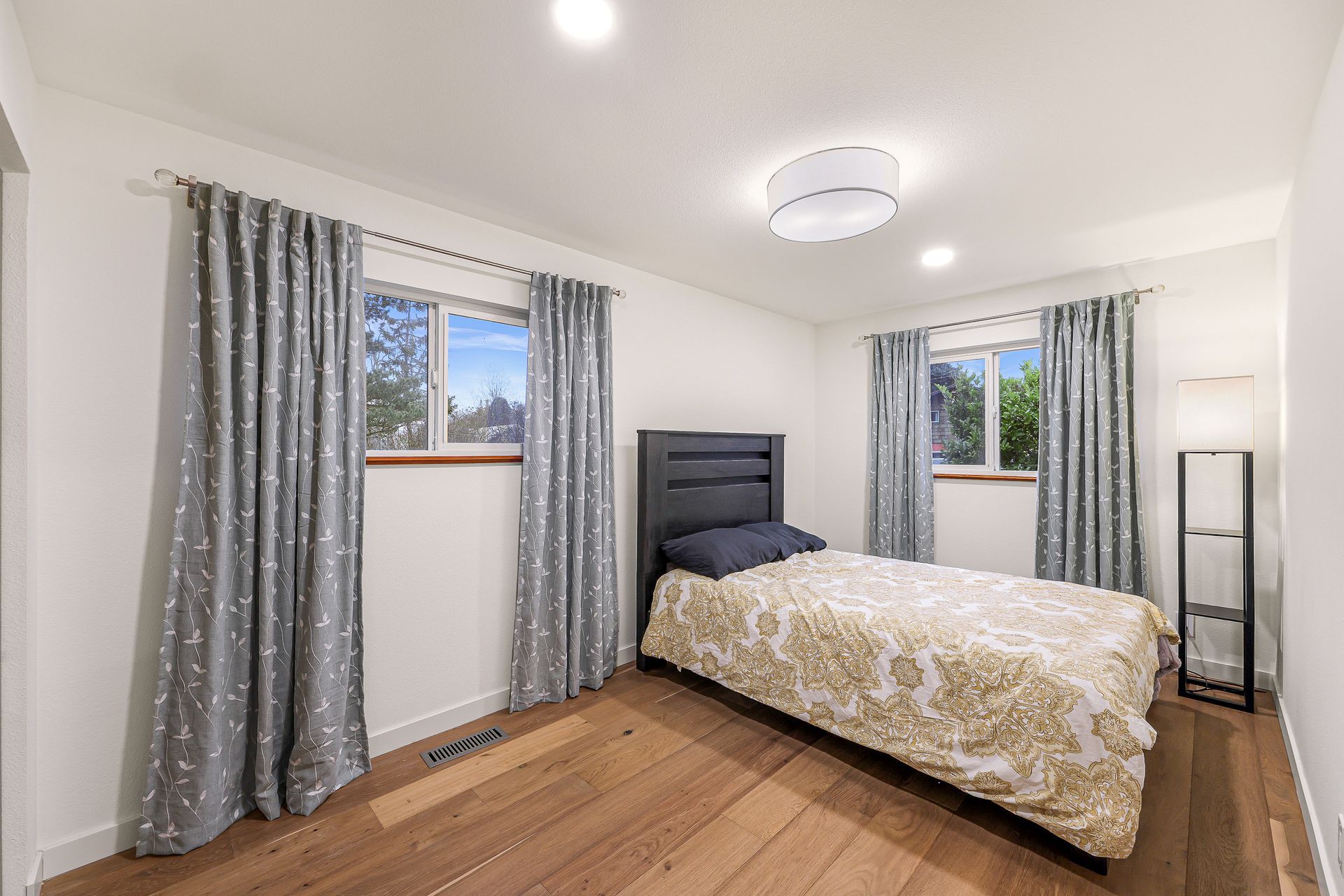 Bedroom with large windows and simple decor.
