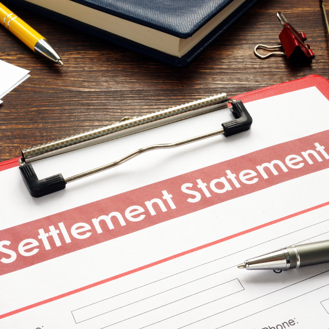 A settlement statement is on a clipboard next to a pen.