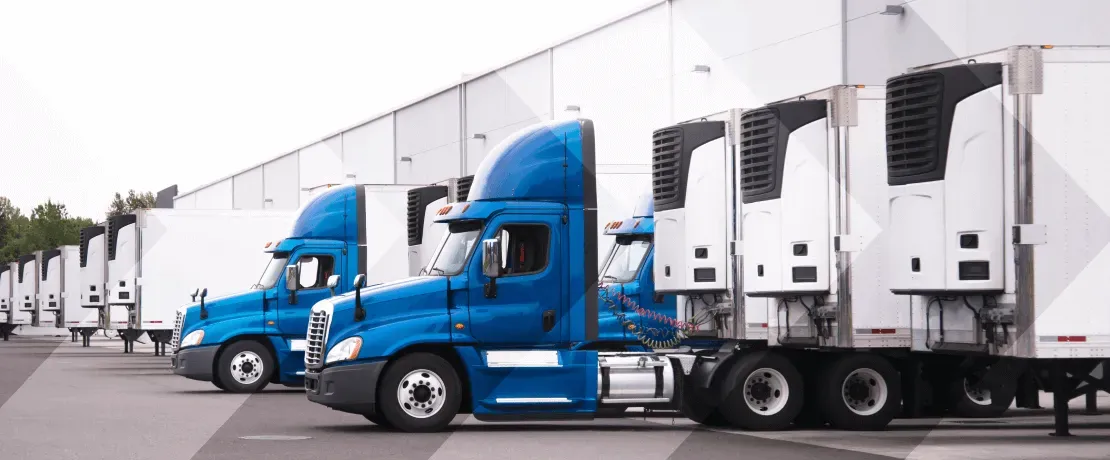 A row of semi trucks parked in front of a warehouse.