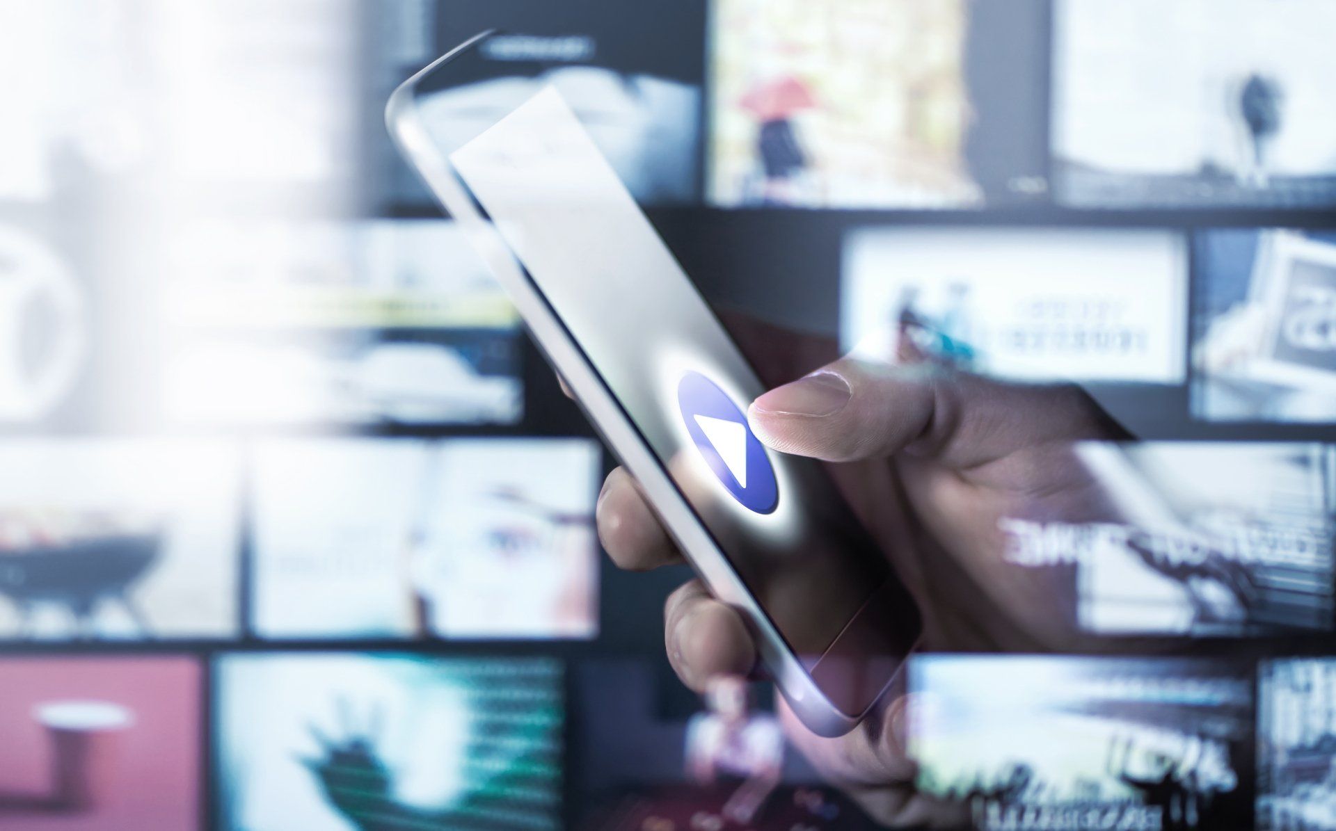 A person is holding a cell phone in front of a television screen.