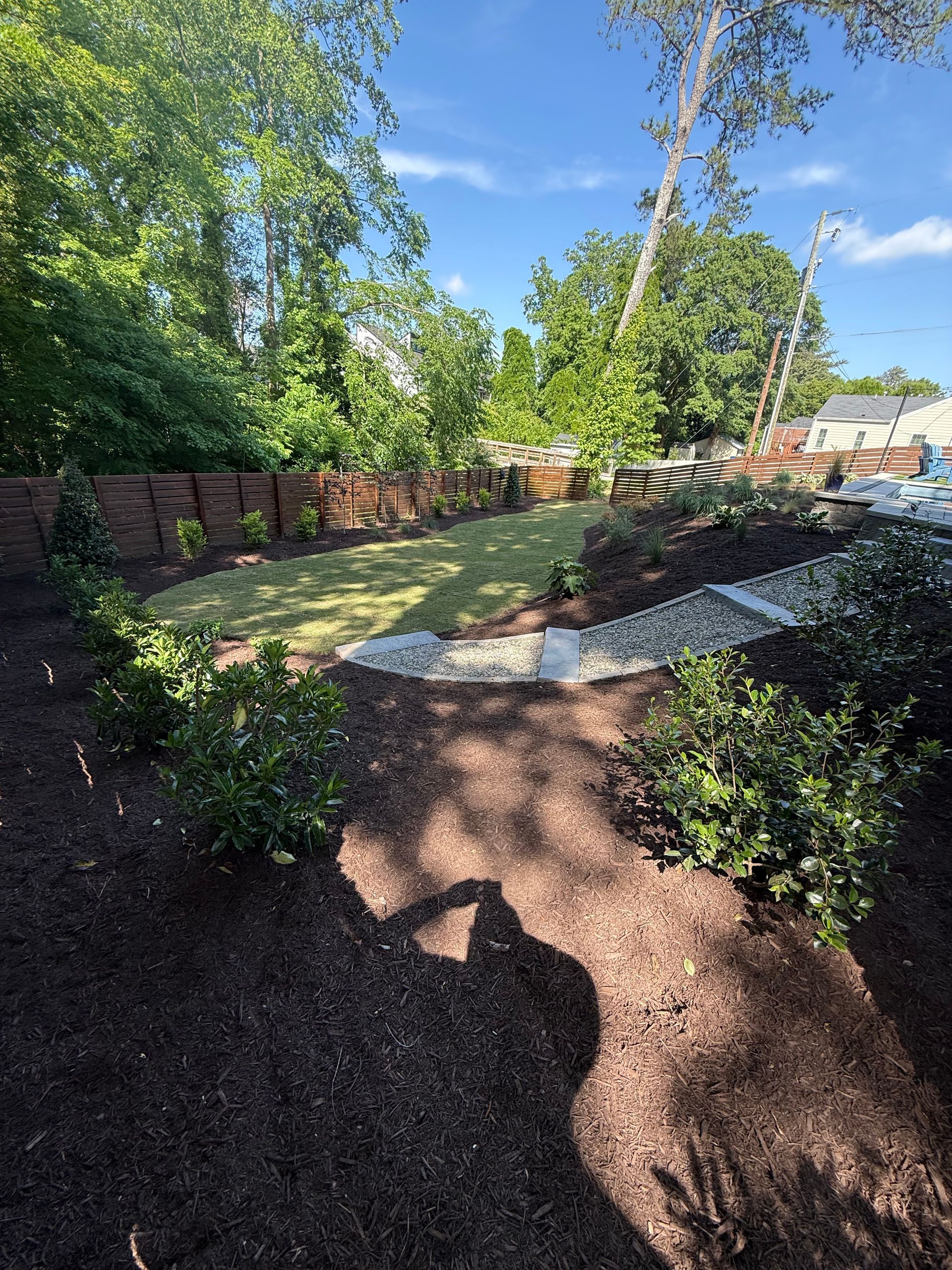 Newly landscaped backyard with mulch, stone borders, and green lawn.