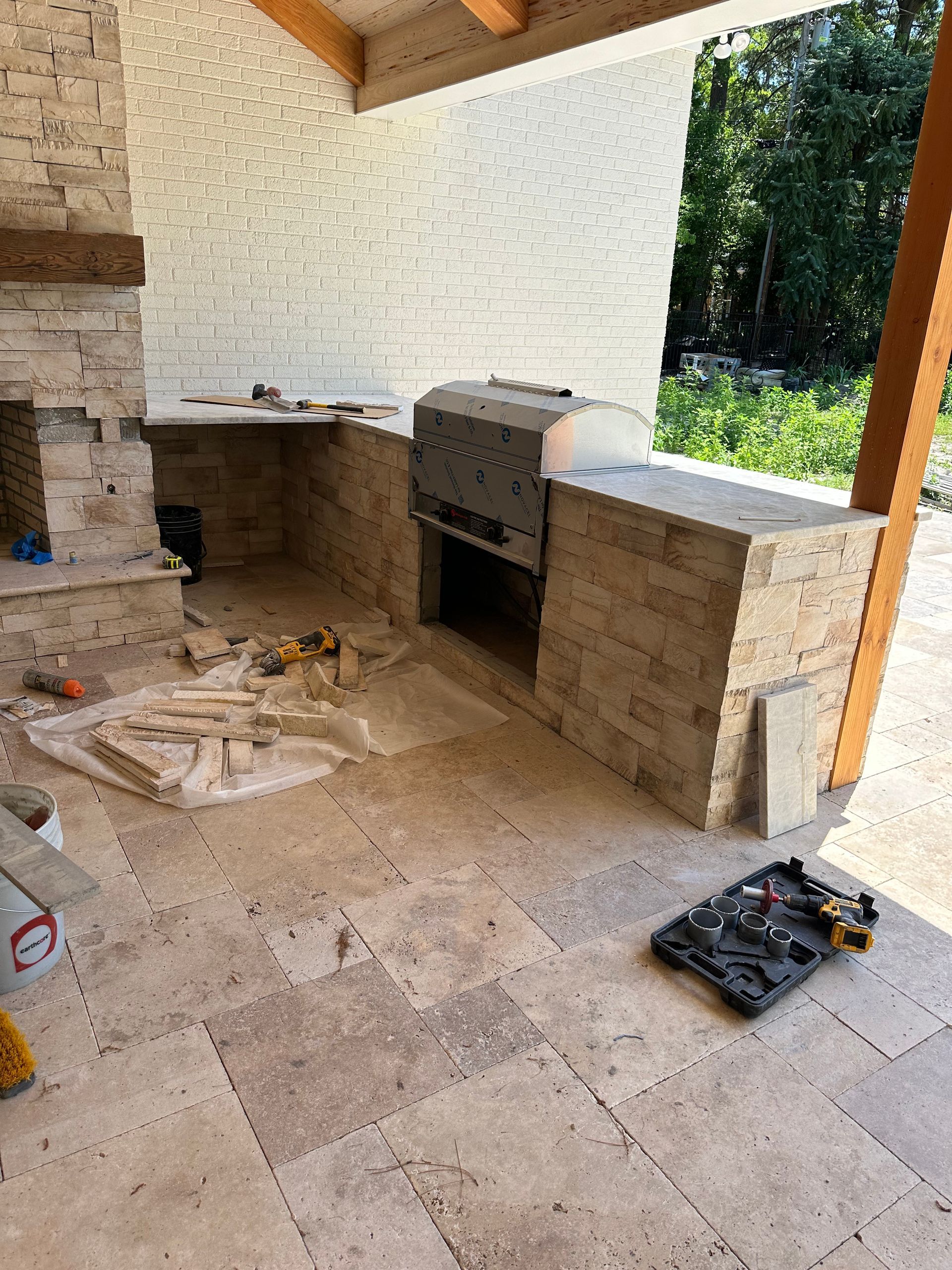 Outdoor kitchen under construction with stone features, counters, and built-in grill and oven.