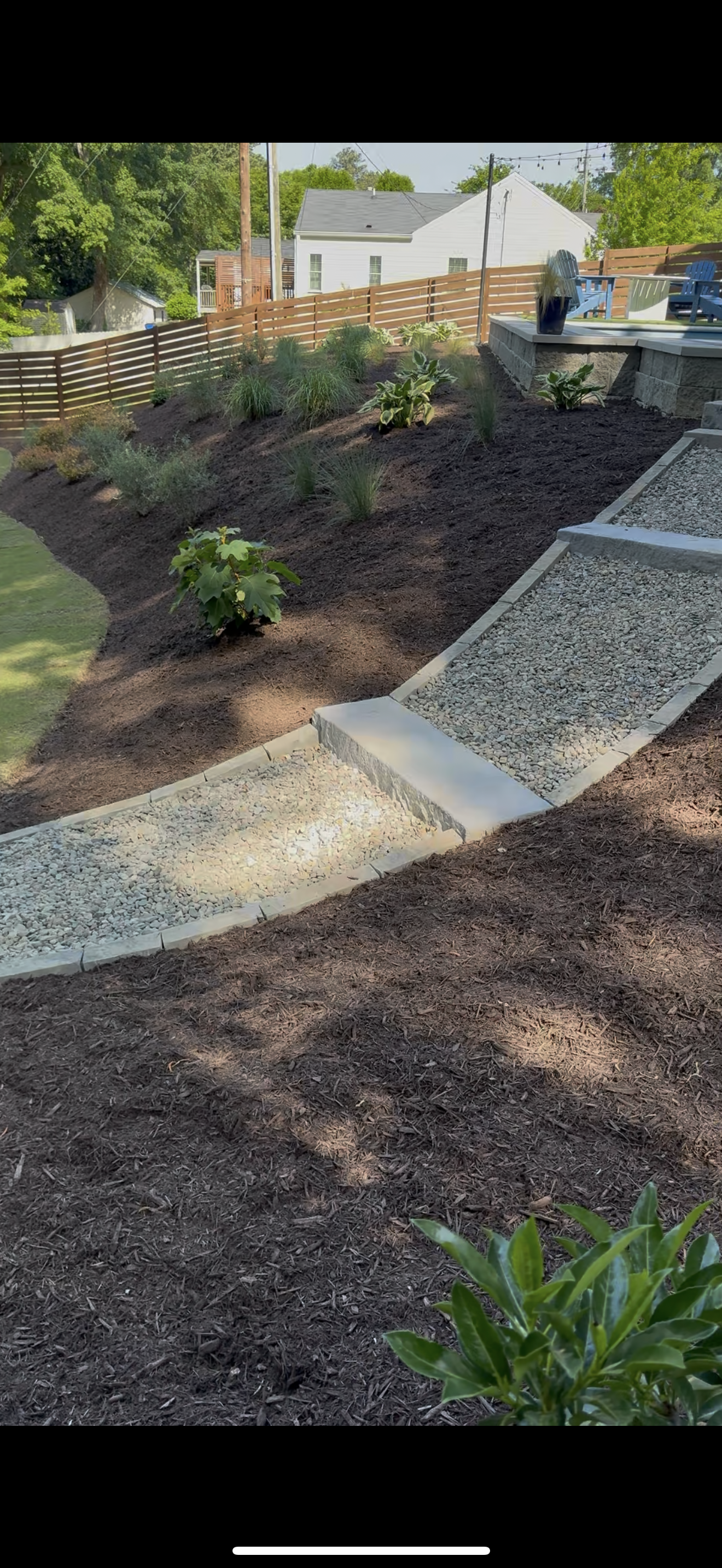 Pathway made of stone gravel with bordering plants and a lawn in a garden.